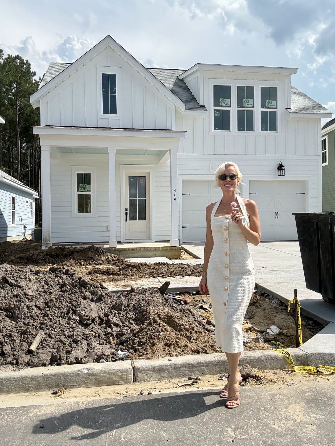 Erica Joy in front of a newly finished white farmhouse-style home